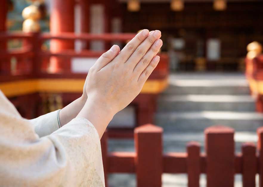 春彼岸 とは何かを考えながら寺院の境内で静かに手を合わせる様子